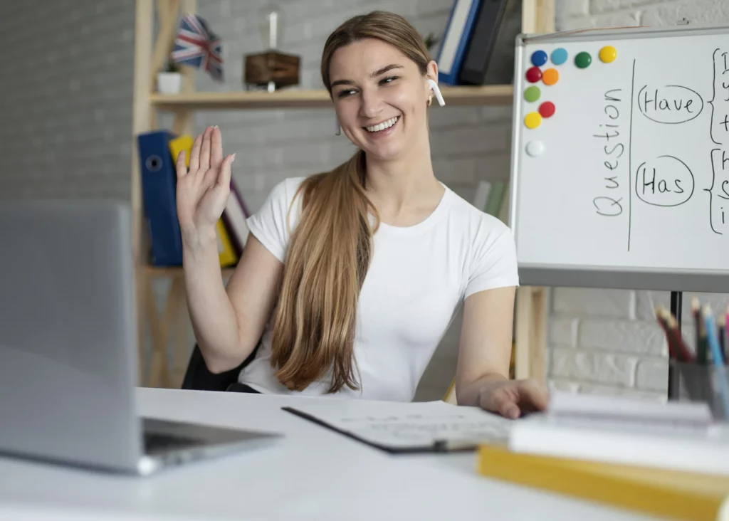 млада девојка ја поздравува камерата на онлајн час по странски јазик